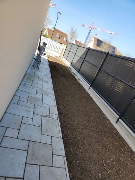 Allée pavée latérale avec clôture à panneaux sombres